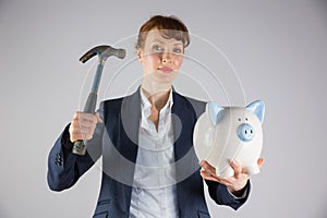 Businesswoman holding hammer and piggy bank