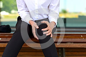 Businesswoman is holding her aching knee