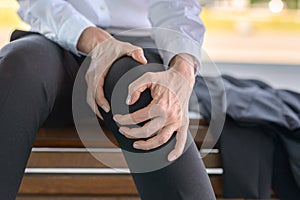 Businesswoman is holding her aching knee