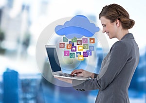Businesswoman holding laptop with cloud apps icons in blue motion public space