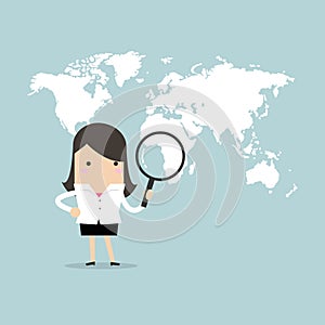 Businesswoman holding magnifying glass finding over world map.