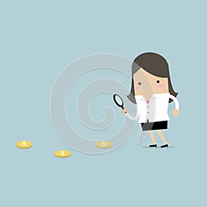 Businesswoman holding a magnifying glass follow dollar coins.