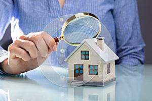 Businesswoman Holding Magnifying Glass Over House Model