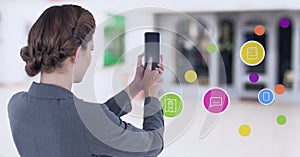 Businesswoman holding mobile phone with apps in shopping mall