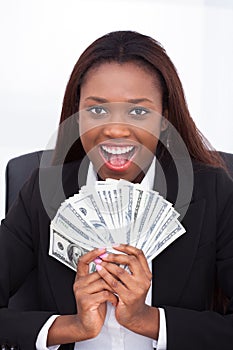 Businesswoman holding money fan in office