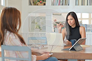 Businesswoman holding a pen pointing at the person sitting opposite She blamed the subordinate work