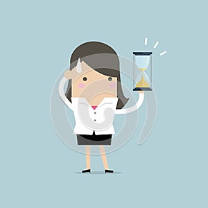 Businesswoman holding sandglass or hourglass, looking and realise it`s nearly time up or deadline.