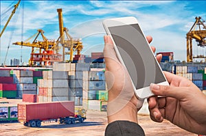 Businesswoman holding smartphone with blurred cargo ship marine background