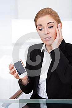 Businesswoman holding smartphone with cracked screen