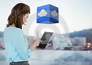 Businesswoman holding tablet with cloud cube with distant city background