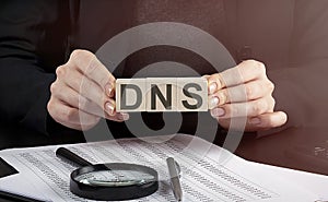 Businesswoman holding wooden block with text DNS , business concept photo