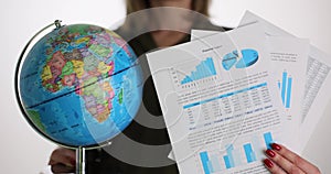 Businesswoman is holding world globe and charts and graphs