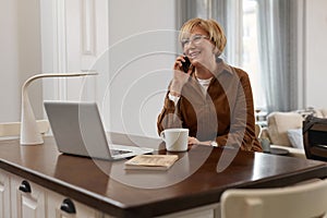 Businesswoman Homework. Female With Laptop. Mature Woman In Brown Jacket And Eyeglasses Talks On Phone.
