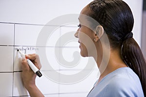 Businesswoman indoors writing on erasable board
