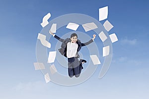 Businesswoman jumping with papers