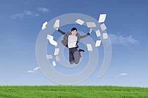 Businesswoman jumping and throwing papers