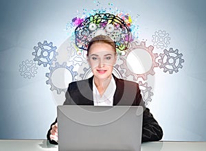 Businesswoman with laptop, colourful brain sketch with gears on background