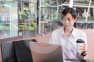 businesswoman with laptop computer sitting outside office building. young asian woman analyzing investment charts outdoors.