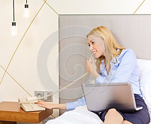 Businesswoman with laptop and phone in hotel room