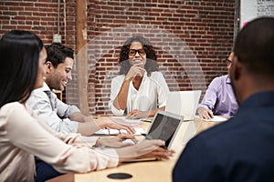 Businesswoman Leading Office Meeting Of Colleagues Sitting Around Table