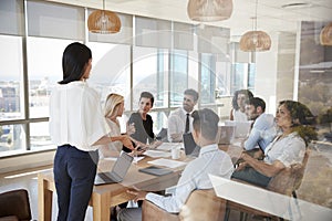 Businesswoman Leads Meeting Around Table Shot Through Door