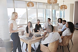 Businesswoman Leads Meeting Around Table Shot Through Door