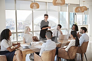 Businesswoman Leads Meeting Around Table Shot Through Door