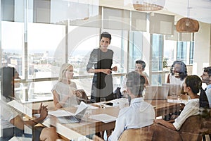 Businesswoman Leads Meeting Around Table Shot Through Door