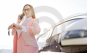 Businesswoman leaning on her car with phone