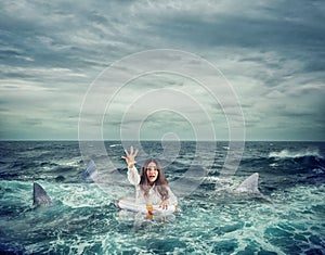 Businesswoman with lifebelt surrounded by sharks asks help