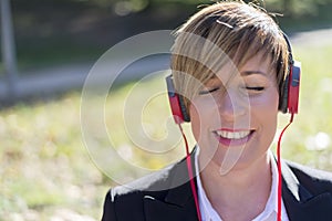 Businesswoman listening to the music with headphones in a park w