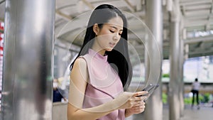 Businesswoman with long black hair text messaging on smartphone, on the move, business, connectivity, happiness