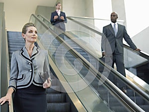 Businesswoman Looking Away While Moving Down On Escalator
