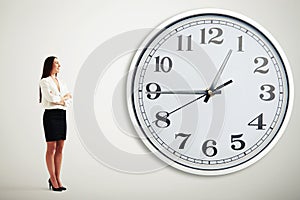 Businesswoman looking at big white clock