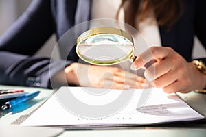 Businesswoman Looking At Contract Form Through Magnifying Glass