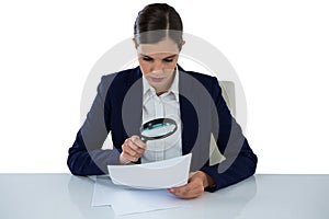 Businesswoman looking at document through magnifying glass