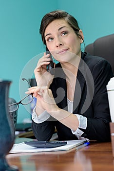 businesswoman looking impatient while listening to person on telephone