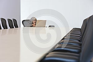 Businesswoman Looking At Laptop In Board Room