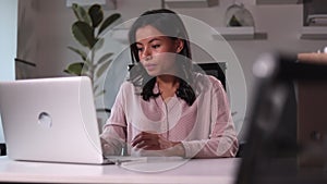 Businesswoman looking at laptop screen and sitting at table in modern office spbi.