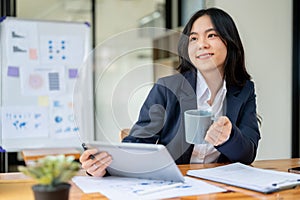 A businesswoman is looking out the window and daydreaming while working at her desk