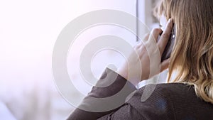 Businesswoman looking out of window while having conversation over mobile phone