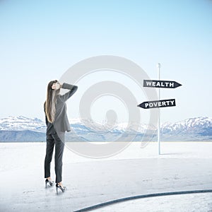 Businesswoman looking on poverty and wealth sign post