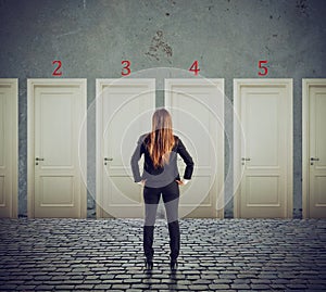 Businesswoman looking to select the right door. Concept of confusion and competition