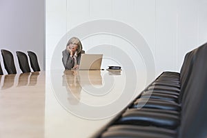 Businesswoman Looking Up By Laptop In Board Room