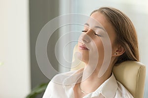 Businesswoman lying on back chair with closed eyes photo