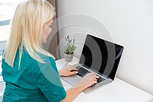Businesswoman making video call to business partner using laptop. Close-up rear view of young woman having discussion