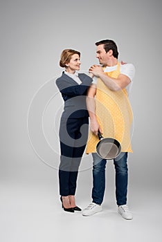 businesswoman and male householder standing together with frying pan feminism concept