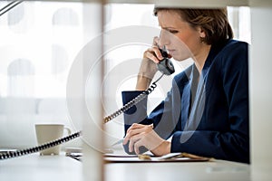 Businesswoman or manageress talking on a landline phone photo