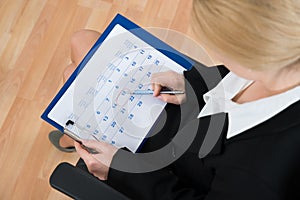 Businesswoman Marking Date On Calendar