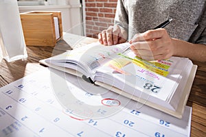 Businesswoman Marking Schedule On Calendar